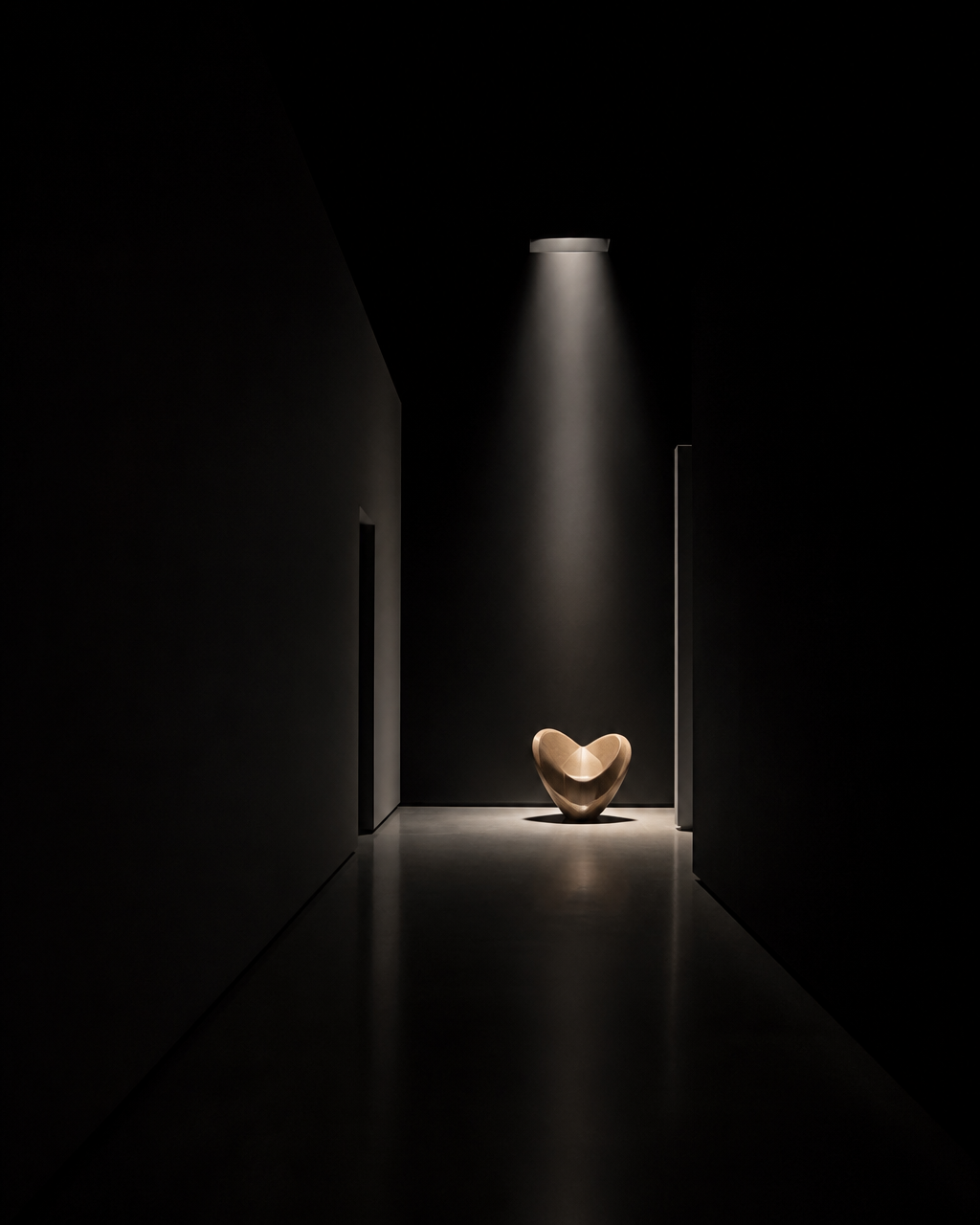 A narrow corridor with a single spotlight falling on a chair.